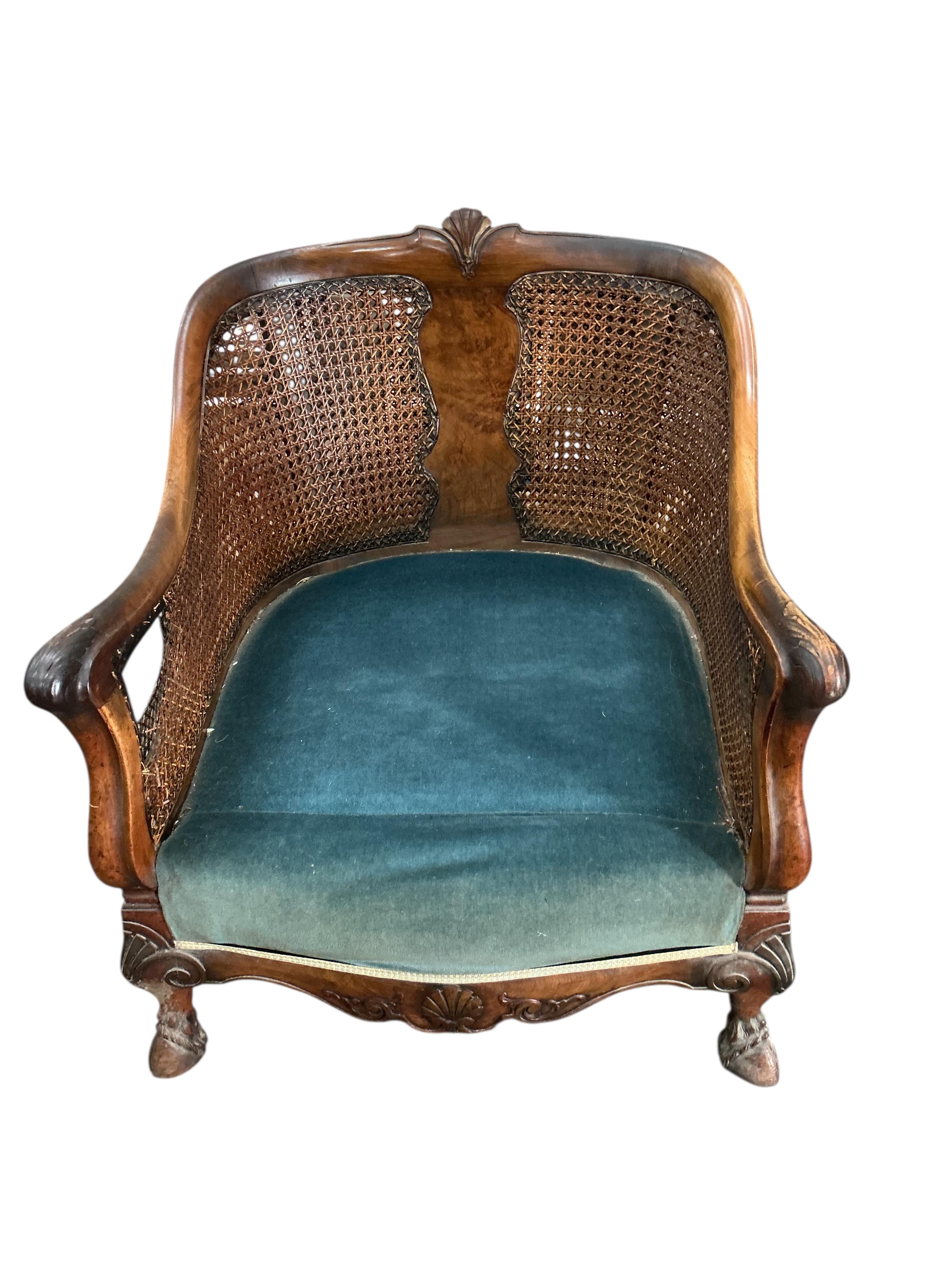 An early 20th century carved walnut and double canework three piece bergère suite, cane in need of repair